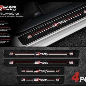 May include: A set of four black carbon fiber-look door sill protectors featuring the Gazoo Racing logo in red, white, and black. Each rectangular strip includes a horizontal red and white stripe design with the GR Sport emblem on both ends.