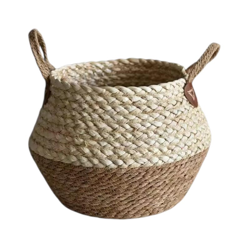 May include: A round woven basket featuring a two-tone design with a light beige upper section and a darker brown lower section. The basket includes two sturdy handles attached with brown leather-like tabs on opposite sides of the rim.