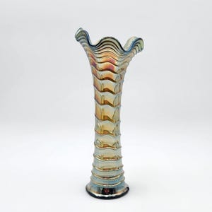 May include: A tall, slender glass vase featuring a distinct iridescent finish with a metallic sheen. The surface displays a repeating horizontal ribbed pattern that extends from the base to the flared, ruffled rim, creating a wavy silhouette.