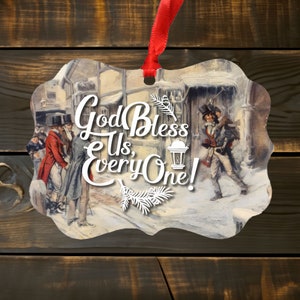 Puede incluir: Adorno con una escena invernal vintage con figuras con ropa de época y el texto "God Bless Us, Everyone!". El adorno tiene una cinta roja para colgar y está sobre un fondo de madera.