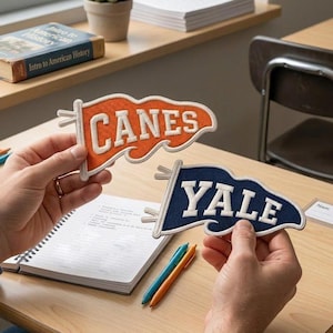 May include: Two embroidered pennant patches with white borders. One patch is orange with the white text CANES, and the other is navy blue with the white text YALE. Both pennants feature a wavy edge design and two small loops on the left side.