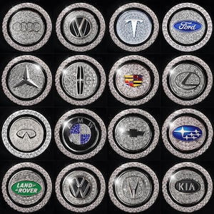 May include: A collection of car emblem accessories, each featuring a different brand logo. The logos are set against a sparkling, diamond-like background and framed by a ring of clear crystals. Brands include Audi, Volkswagen, Tesla, Ford, and more.