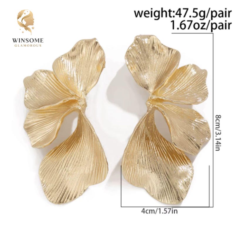 May include: A pair of gold-toned metal earrings shaped like large, textured flower petals. Each earring measures 3.14 inches in height and 1.57 inches in width, with a combined weight of 1.67 ounces per pair. The brand name WINSOME GLAMOROUS is visible.