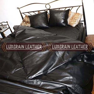 May include: A bed with black leather bedding, including a comforter and two square pillows. Two decorative pillows with a leopard print pattern are also visible. The headboard is made of wrought iron. The text "LUXGRAIN LEATHER" is displayed.