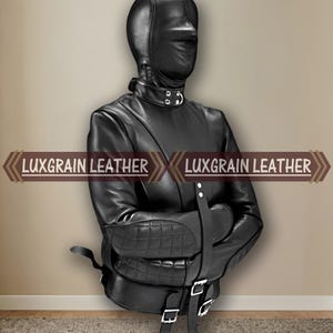 Può includere: Una giacca di contenzione in pelle nera con cappuccio integrale, colletto alto con anello a D in metallo e gomitiere trapuntate. Il capo presenta diverse cinghie regolabili con fibbie color argento e la scritta LUXGRAIN LEATHER.