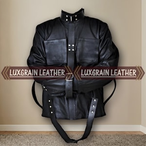 May include: A black leather jacket with a high collar, two front pockets, and a belt. The jacket has straps and is fastened with buckles and snaps. The text "LUXGRAIN LEATHER" is displayed on the image.