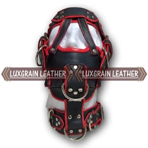 May include: A black and red leather hood with metal rings and straps. The hood has a clear panel in the front and the text "LUXGRAIN LEATHER" is displayed across the front.