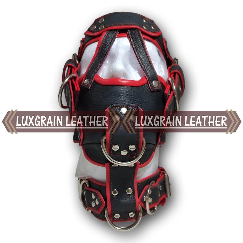 May include: A black and red leather hood with metal rings and straps. The hood has a clear panel in the front and the text "LUXGRAIN LEATHER" is displayed across the front.