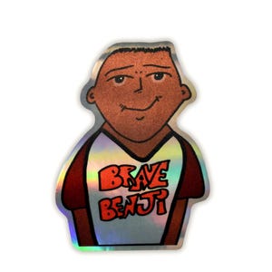 May include: A holographic sticker featuring a cartoon illustration of a person with brown skin. The person is wearing a white and maroon shirt with the words "Brave Benji" in orange and red. The sticker has a shiny, iridescent finish.