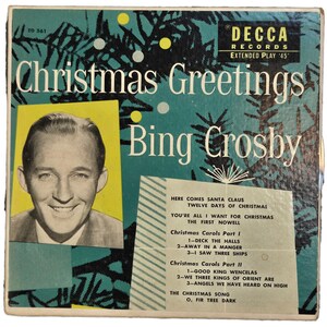 May include: A square Decca Records extended play 45 vinyl record cover titled Christmas Greetings by Bing Crosby. The teal background features black pine tree silhouettes, yellow and white circles, a portrait of Bing Crosby, and a tracklist.