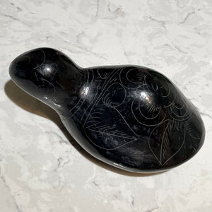 May include: A black ceramic bird figurine with a detailed floral design carved into the surface.