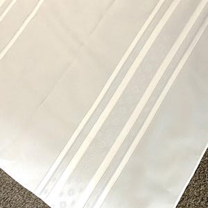 May include: White fabric with a vertical stripe pattern. The stripe is made of a white fabric with a small, repeating circle design.