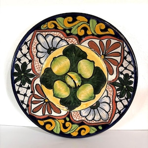 May include: Hand-painted ceramic plate with a vibrant design. The plate features a central motif of yellow lemons surrounded by green leaves, set against a yellow background. The border is a deep blue, with floral and geometric patterns in red, white, and green.