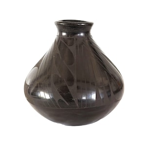 May include: A polished black ceramic vase with a rounded body and a narrow neck. The surface features a matte-finish geometric pattern consisting of repeating curved shapes and vertical lines that contrast against the glossy black finish.