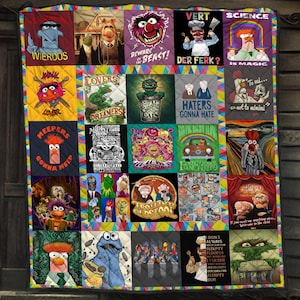 May include: A quilted throw blanket featuring a grid of twenty-five distinct squares, each displaying colorful Muppets character illustrations and text such as Science is Magic, Haters Gonna Hate, and The Muppet Show, finished with a multi-colored triangular border.