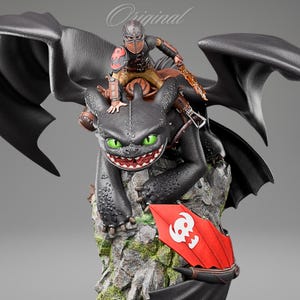 May include: A detailed figurine of a black dragon with bright green eyes and a wide, toothy grin, carrying a rider in dark armor. The dragon is perched on a textured, rocky base featuring a red shield with a white skull emblem and orange flames.