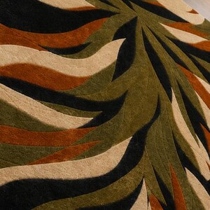 May include: A textured area rug featuring a repeating radial pattern of curved, wave-like shapes in alternating shades of black, olive green, burnt orange, and cream. The surface has a distinct, fine-grained, embossed or carved texture.