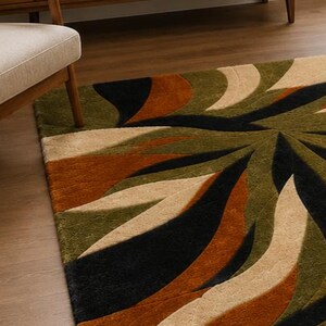 May include: A rectangular area rug featuring a large-scale, swirling abstract pattern. The design consists of curved, organic shapes in deep olive green, burnt orange, black, and cream, with a textured, tufted pile surface throughout the rug.