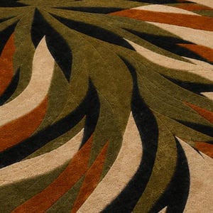 May include: A textured rug featuring a radial pattern of curved, leaf-like shapes in shades of olive green, burnt orange, cream, and black. The surface displays a consistent, intricate embossed swirl design across all colored segments.