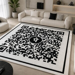 Può includere: Un grande tappeto rettangolare caratterizzato da un design ad alto contrasto in bianco e nero. Il motivo consiste in un complesso codice QR pixelato con un emblema circolare centrale contenente il carattere devanagari per la lettera Pe.