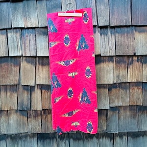 May include: Red fabric with a black and white print of Darth Vader characters. The fabric is hanging on a wooden wall.