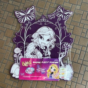 May include: A Bratz shaped fuzzy poster featuring a purple and white illustration of a character with long hair, butterflies, and mushrooms. The packaging includes the text Bratz Shaped Fuzzy Poster, Easy to Color, and Mistakes Never Show.
