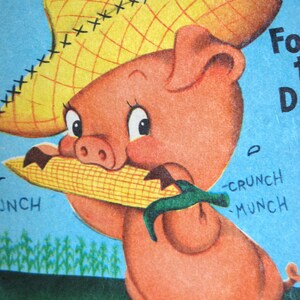 May include: A cartoon pig wearing a straw hat with red stitching and holding a yellow corn cob. The pig is pink with a red nose and big eyes. The background is blue with the words "SIGHTS and SOUNDS" in red and white letters.