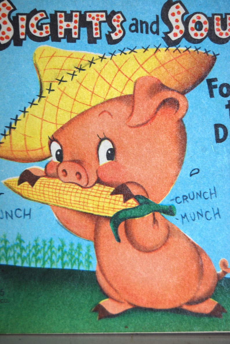 May include: A cartoon pig wearing a straw hat with red stitching and holding a yellow corn cob. The pig is pink with a red nose and big eyes. The background is blue with the words "SIGHTS and SOUNDS" in red and white letters.