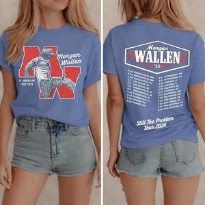 May include: A blue t-shirt featuring a graphic of Morgan Wallen's name and tour dates. The front of the shirt has a red and white design with the text "N. AMERICAN TOUR 2026". The back of the shirt has a list of tour dates.