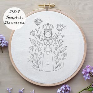 Pode incluir: Um bastidor de bordado com um desenho bordado à mão de uma figura religiosa rodeada por flores. A figura usa uma coroa e uma capa com um coração e uma cruz. O texto "PDF Template Download" é visível. Moldura de madeira.