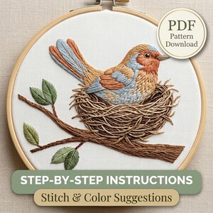 May include: An embroidery hoop containing a white fabric panel with a stitched design of a bird in a nest on a branch. The bird has orange, blue, and tan thread details. The nest and branch are brown, and the leaves are green. Includes PDF text.