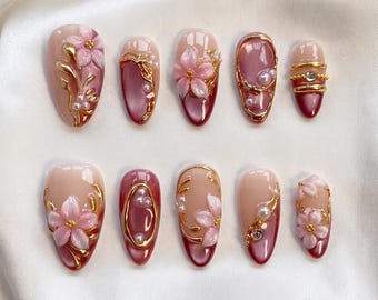 Unghie finte di lusso con decorazioni floreali 3D dorate a mandorla, elegante manicure artigianale con perle.