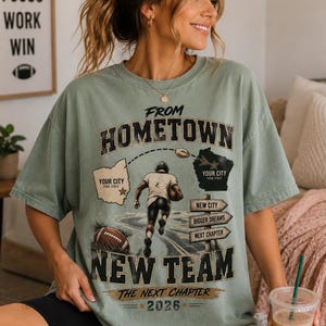 Peut inclure: Un t-shirt à manches courtes vert sauge avec un graphisme représentant un joueur de football américain courant sur une route. Le texte indique FROM HOMETOWN NEW TEAM, THE NEXT CHAPTER 2026, avec deux cartes et des espaces pour YOUR CITY et YOUR STATE.
