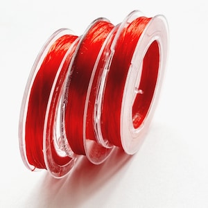 May include: Four spools of red thread wound around each other. The thread is wrapped around clear plastic spools.