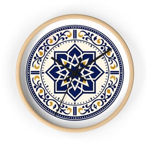 Puede incluir: Reloj de pared redondo con marco de madera clara. La esfera del reloj presenta un fondo color crema con un diseño geométrico azul marino y dorado. Las manecillas son negras.