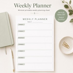 May include: A minimalist weekly planner with the text "Weekly Planner" at the top. The planner includes sections for each day of the week, from Monday to Sunday. A pen, notebook, and small dish with paper clips are also visible.
