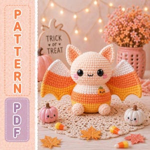 May include: A crochet bat toy featuring a candy corn color scheme of white, orange, and yellow. The bat has large black eyes, a small embroidered mouth, and a tiny pumpkin applique on its chest. The text PATTERN PDF is visible on the left.