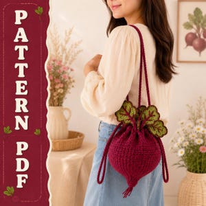 May include: A crochet drawstring bag shaped like a deep red beet with green and brown leafy tops. The bag features long, thin matching red straps and a textured, rounded body. The text "PATTERN PDF" is displayed vertically on the left side.