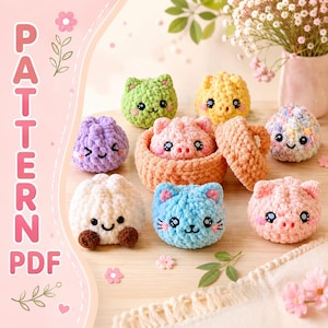 Puede incluir: Una colección de pequeñas figuras de peluche tejidas a ganchillo en varios colores, incluyendo verde, amarillo, morado, blanco, azul y rosa. Algunas parecen gatos y cerdos con ojos de seguridad negros y caras bordadas. Una cesta tejida color melocotón contiene un peluche de cerdo. El texto "PATTERN PDF" es visible a la izquierda.