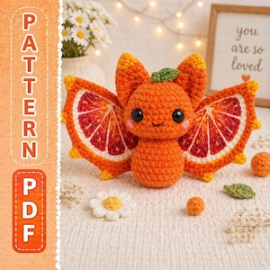 May include: A crocheted orange-colored creature with large wings resembling orange slices. The creature has black eyes and a small green leaf on its head. The image also includes a crocheted daisy, small orange balls, and the text "PATTERN PDF".