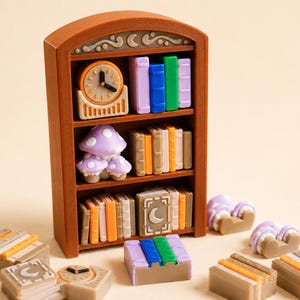 May include: A brown miniature bookshelf with three shelves containing small colourful books, a clock, and mushroom figures. Several loose miniature book stacks, mushroom figures, and a clock are arranged in front of the standing bookshelf unit.