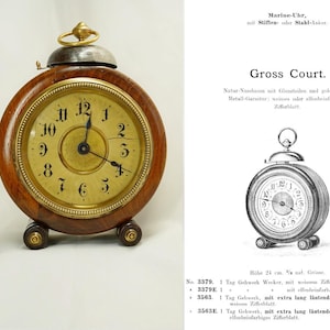 May include: A vintage wooden alarm clock with a gold-colored face and black numerals. The clock has a round shape, a small bell on top, and rests on small, round feet. The clock face reads "Gross Court."