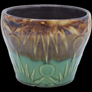 Pode incluir: Um vaso de cerâmica marrom e verde com um design geométrico. O vaso tem uma borda larga e uma base alargada.