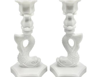 May include: A pair of white milk glass candle holders shaped like a fish with a rosebud on top.