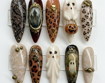 May include: A set of ten Halloween-themed nail designs. The nails feature various designs, including lace, a haunted house, leopard print, a skull, ghosts, and a pumpkin. The color palette includes black, brown, orange, and white.