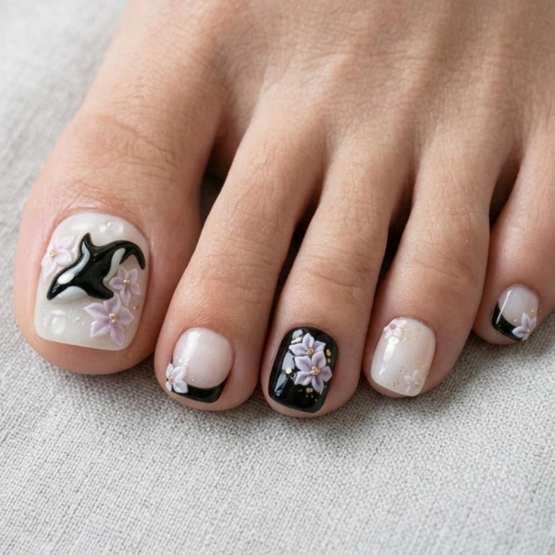 Peut inclure: Ongles d'orteils avec une manucure d&eacute;corative pr&eacute;sentant un motif d'orque noir et blanc sur le gros orteil, agr&eacute;ment&eacute; de fleurs violet clair en relief. Les autres ongles pr&eacute;sentent un m&eacute;lange de noir uni, de blanc transparent et de fleurs.