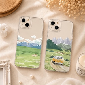 Könnte beinhalten: Zwei transparente Smartphone-Hüllen mit aufgedruckten Landschaftsillustrationen. Die linke Hülle zeigt eine grüne Wiese mit fernen blauen Bergen und einem kleinen Haus. Die rechte Hülle zeigt einen gelben Van auf einem Weg durch eine grüne Landschaft.