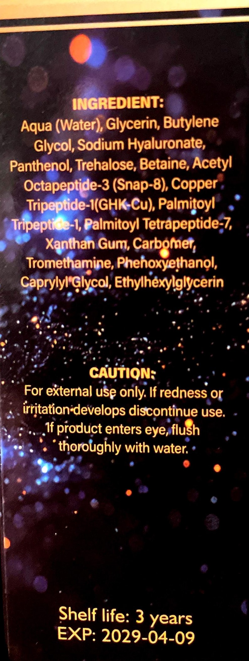May include: A black product label with gold text listing ingredients including Aqua, Glycerin, Sodium Hyaluronate, and various peptides. It includes a caution for external use only and states a shelf life of 3 years with an expiration date of 2029-04-09.