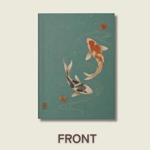 May include: A rectangular notebook with a teal cover featuring an illustration of two koi fish swimming in water. One fish is orange and white, while the other is black and white. Two small orange maple leaves float nearby, and a small red seal is visible.