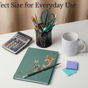 May include: A teal notebook with a koi fish illustration, a black mesh pencil cup containing pens, pencils, and scissors, a gray calculator, a white mug, a black pencil, and two square sticky notes with the text Perfect Size for Everyday Use.